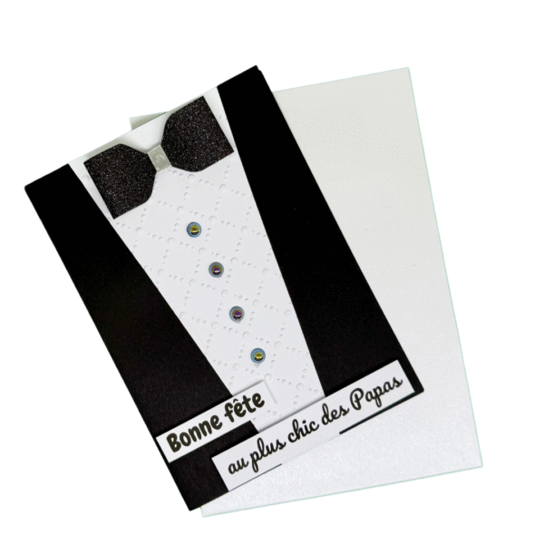 Carte artisanale "Le plus chic des Papas" présentée avec son enveloppe assortie, montrant le design costume et le nœud papillon scintillant