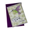 Carte colibri posée sur enveloppe violette, vue de dessus.