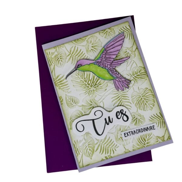 Carte colibri posée sur enveloppe violette, vue de dessus.