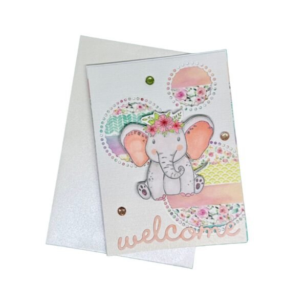 Carte de naissance fille posée devant son enveloppe blanche irisée.