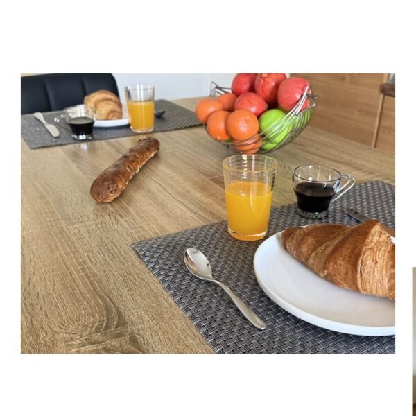 Petit-déjeuner avec un verre de jus d'orange, une tasse de café et un croissant sur un set de table.