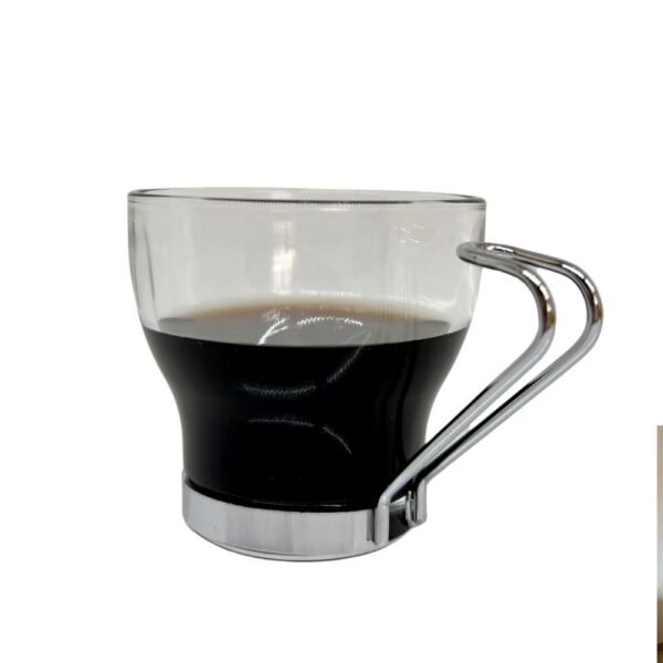 Une tasse en verre et métal contenant un café noir factice en résine sur un fond neutre.