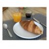 Une mise en scène de petit-déjeuner réaliste réalisée avec des factices alimentaires en résine artisanale : un croissant, un jus d'orange pressée et un café noir sur une table en bois avec un set de table gris. Créations Coq'Ci pour la photographie professionnelle et le home staging